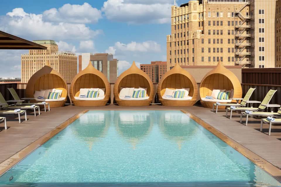 Rooftop pool with gold dome lounges overlooking city skyline
