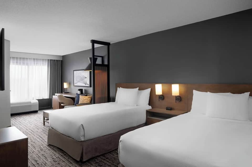 Modern hotel room with two beds, wood headboards, and contemporary decor