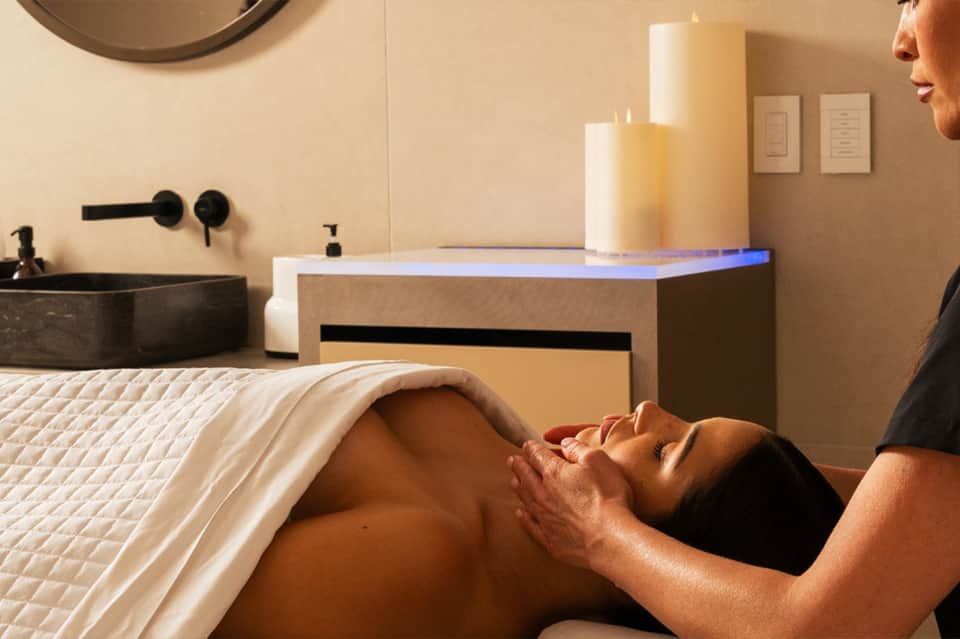 Spa treatment room with massage table, dark sink, and ambient lighting