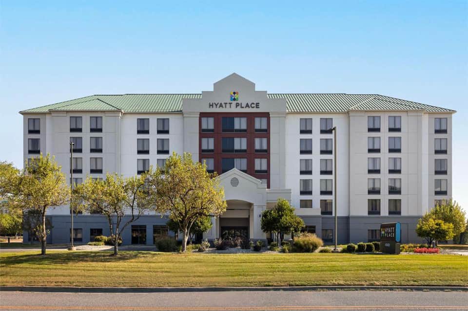 Hyatt Place hotel exterior with white facade, red center section, and landscaped grounds