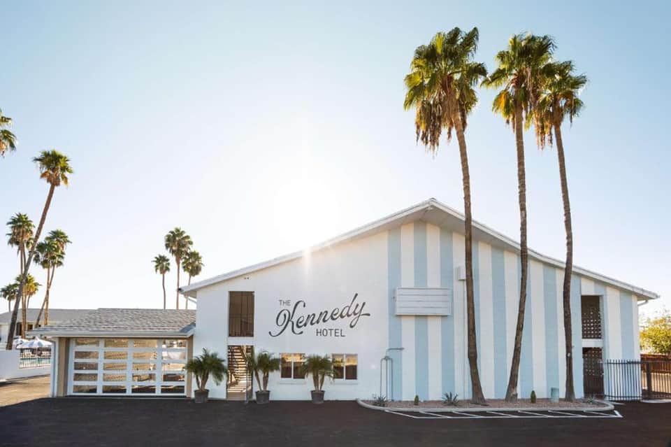 Modern white hotel building with blue and white striped exterior and tall palm trees