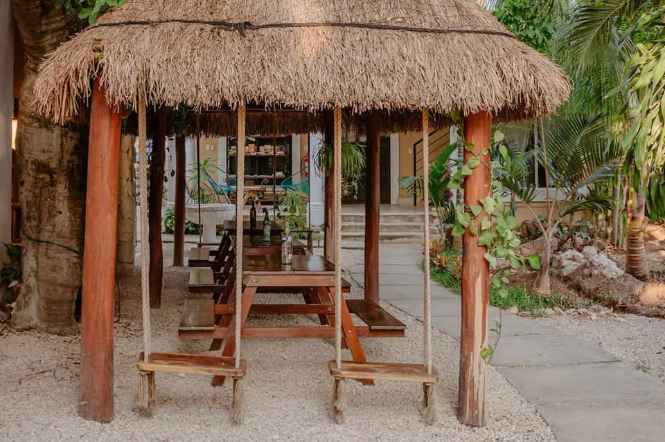 Thatched-roof beachside cabana with wooden benches and tropical vegetation