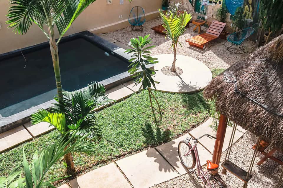 Aerial view of small dark pool with patio furniture and palm trees in courtyard setting