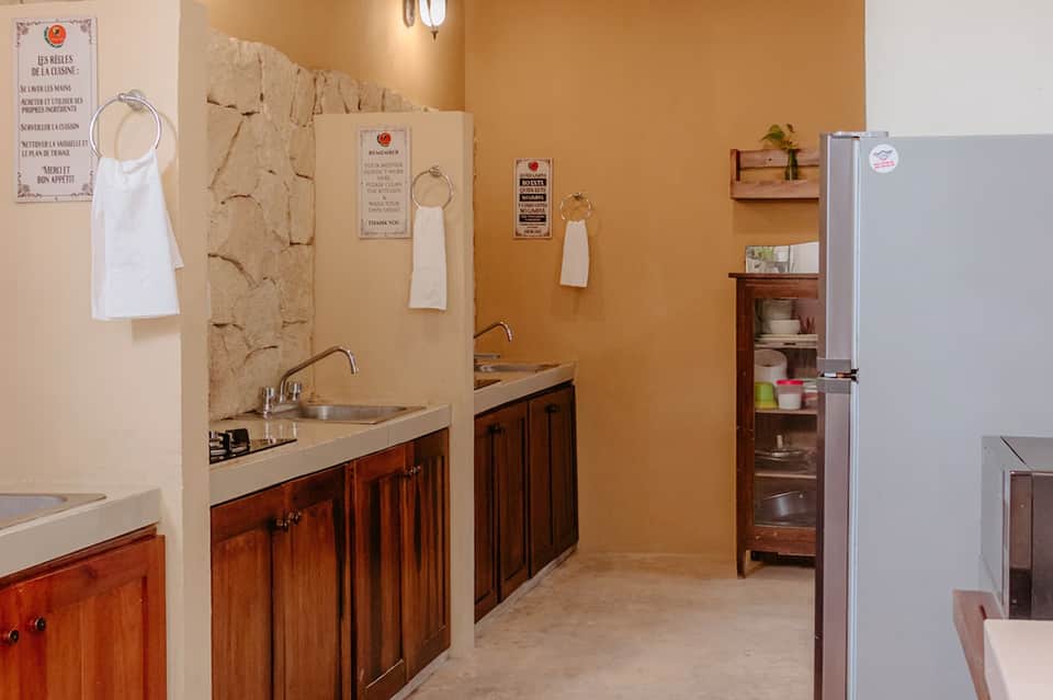 Kitchen prep area with wooden cabinetry, dual sinks, and French culinary instruction posters