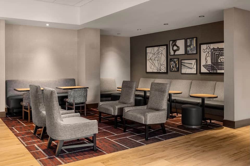 Hotel lounge with gray upholstered chairs, low tables, and contemporary wall art