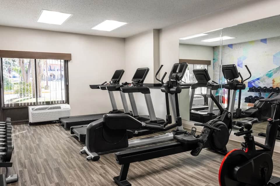 Fitness center with cardio equipment, treadmills, exercise bikes, and natural window lighting