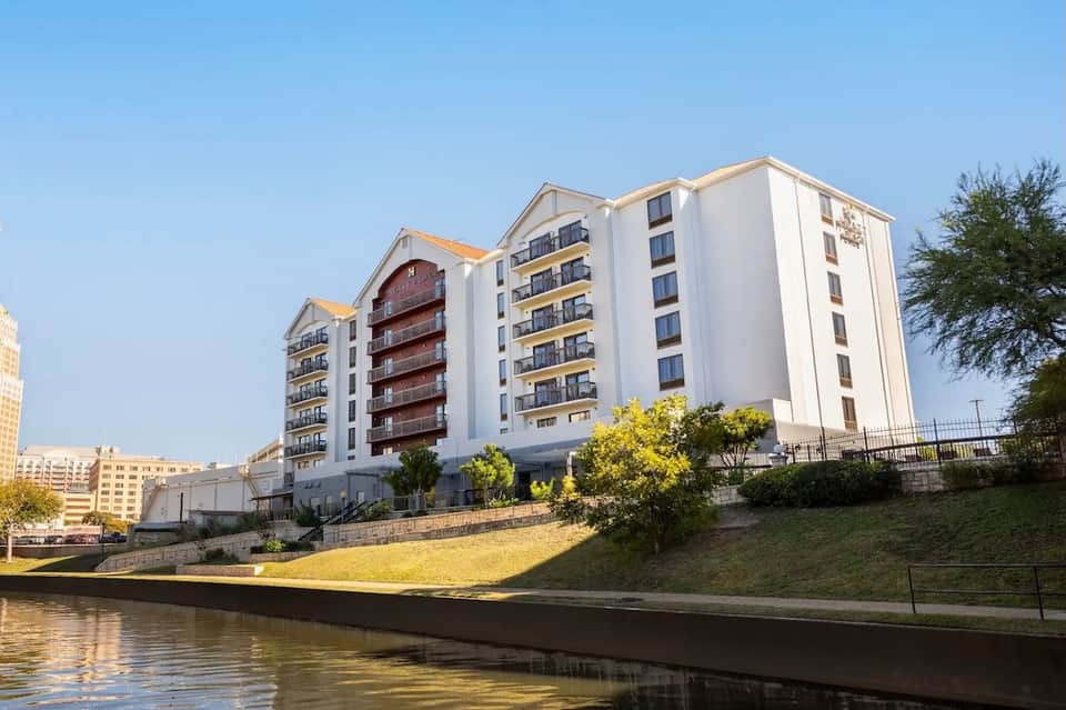 Modern waterfront apartment building with white and brown exterior beside calm river
