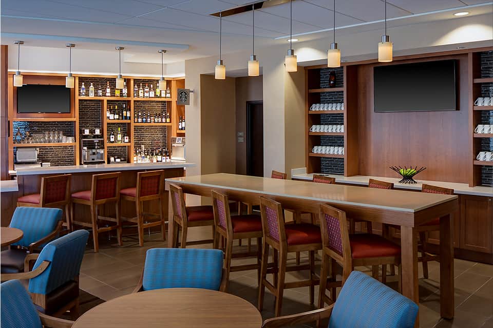 Hotel lounge with wooden bar, seating area, and modern pendant lighting