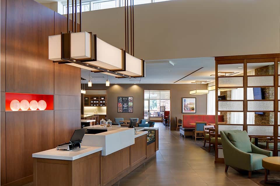 Modern hotel lobby with wood accents, reception desk, contemporary furniture, and open layout design