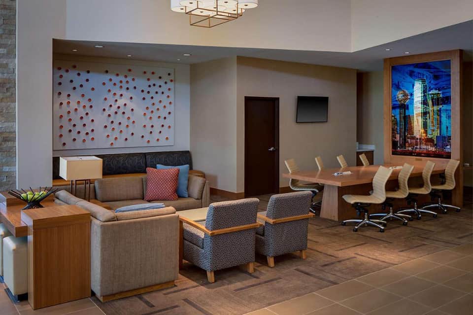Modern hotel lobby lounge with wood furnishings, colorful artwork, and business meeting spaces