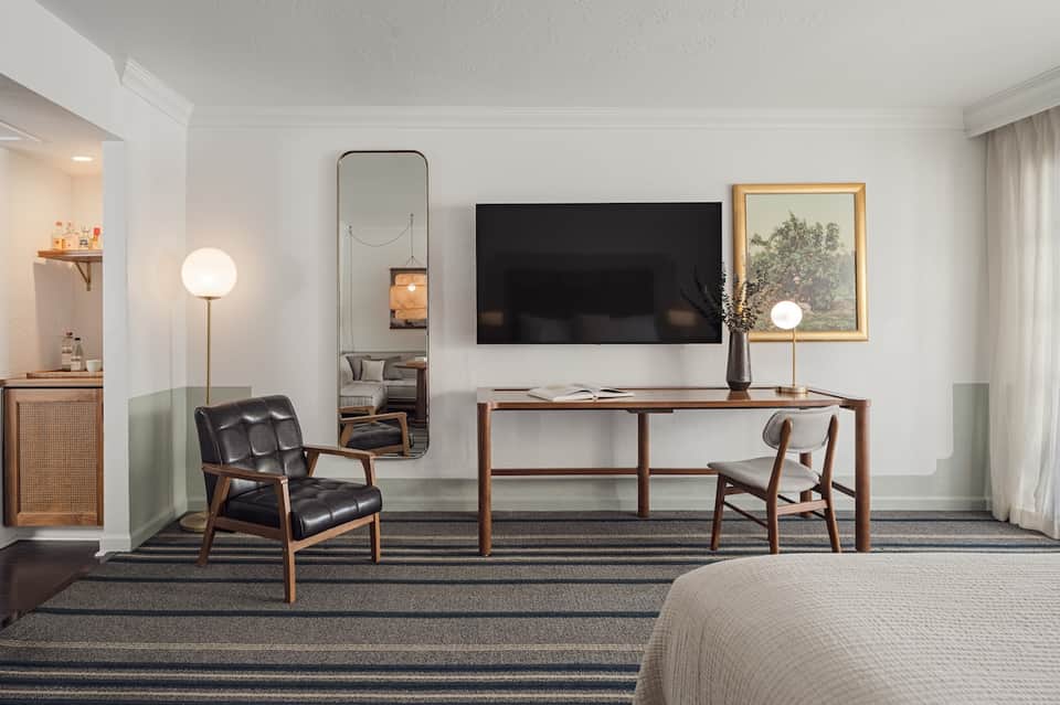 Upscale hotel room with desk, chair, TV, and mid-century modern furnishings