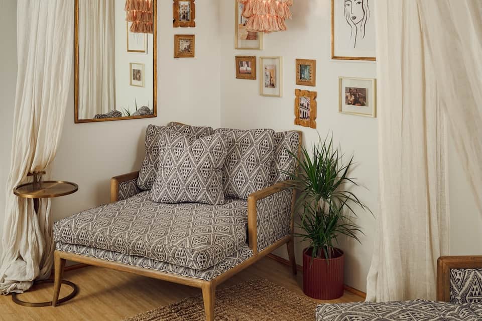 Mid-century modern bedroom with patterned armchair, gallery wall, and neutral decor
