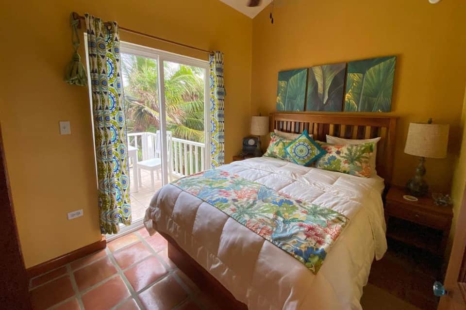 Bright yellow bedroom with tropical bedding, balcony, and palm tree views