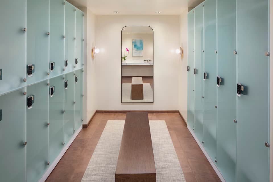 Hotel changing room corridor with frosted glass lockers and mirrored vanity