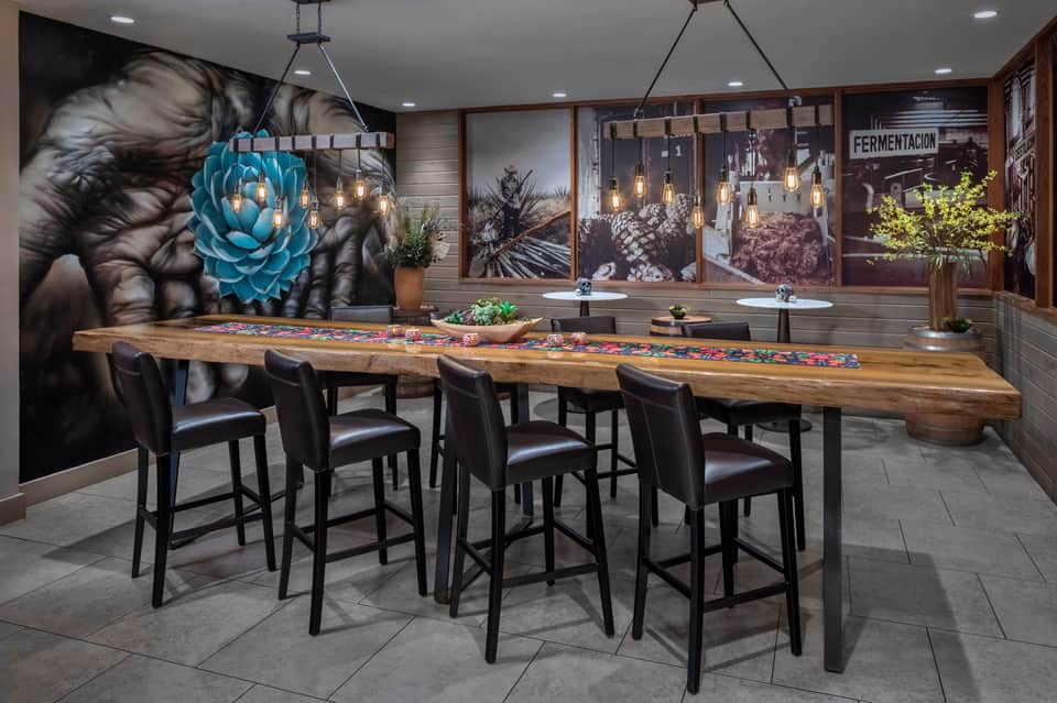 Modern bar with long wooden counter, bar seating, and artistic wall murals