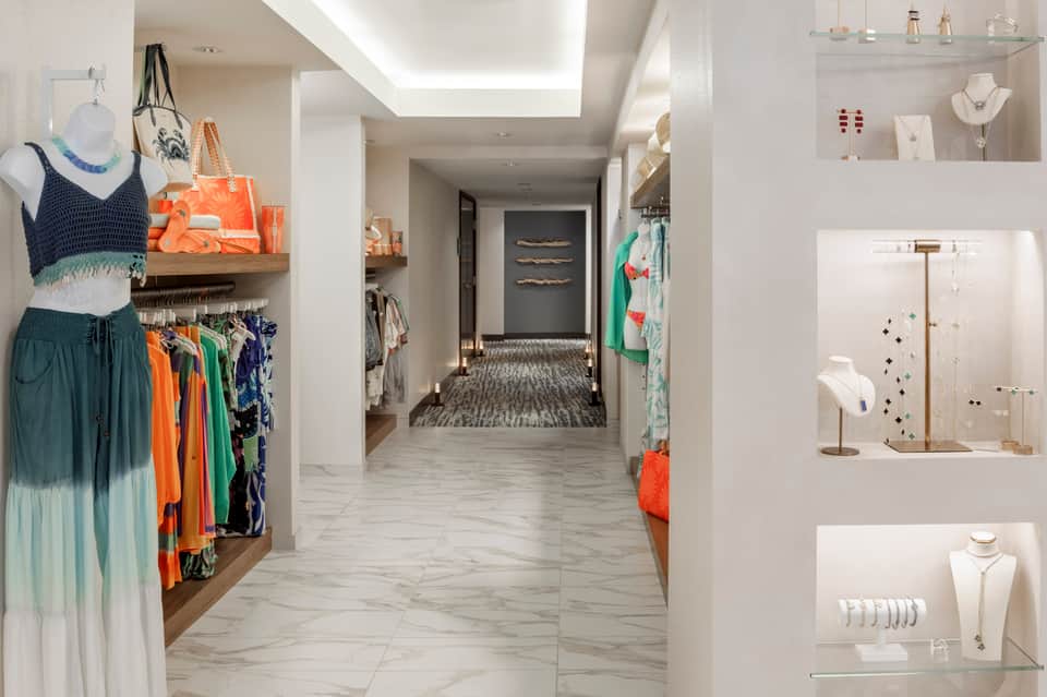 Modern retail corridor with clothing displays, jewelry cases, and colorful merchandise on shelves