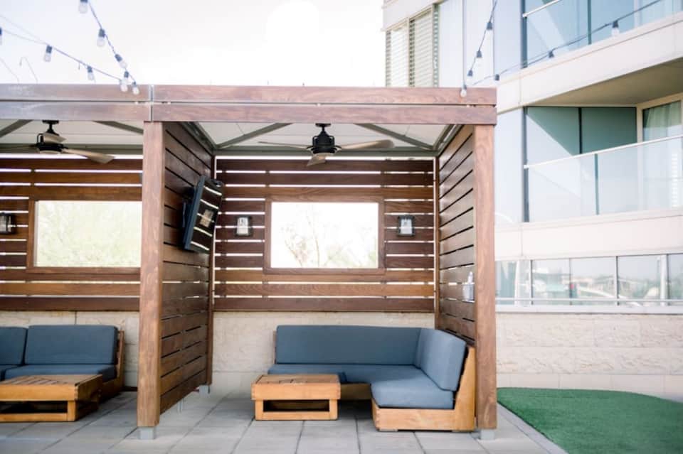 Contemporary wooden pergola lounge area with blue cushioned seating and horizontal slat privacy walls on rooftop deck
