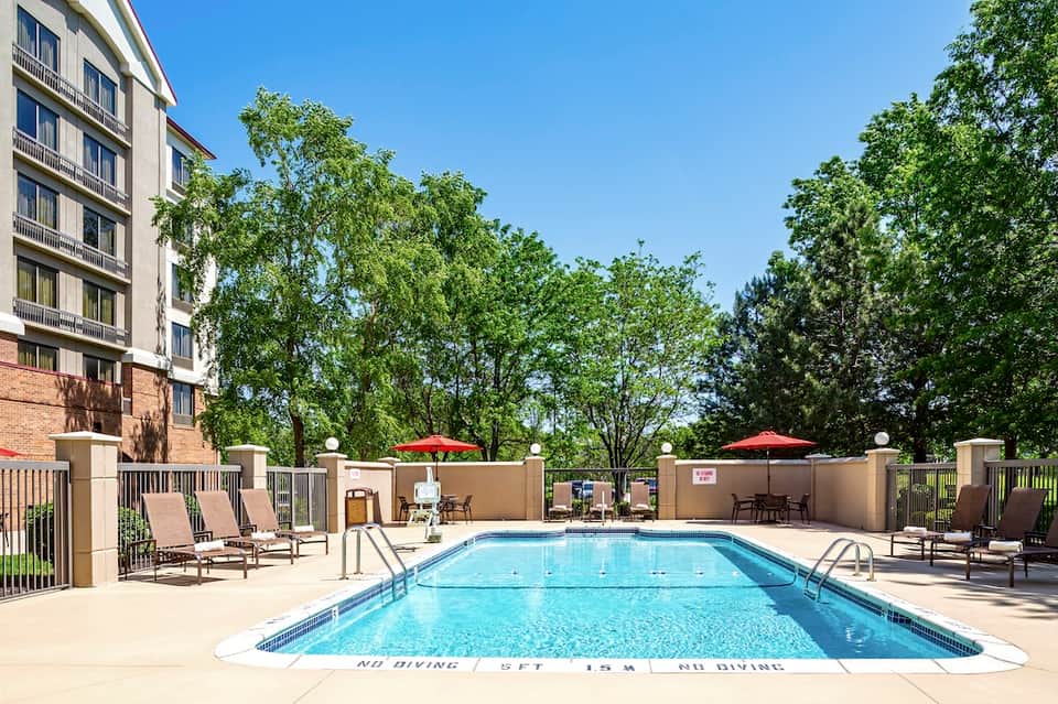 Outdoor swimming pool with loungers, umbrellas, and multi-story residential building