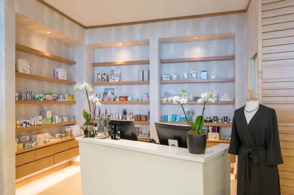 Spa reception desk with illuminated shelving displaying beauty and skincare products