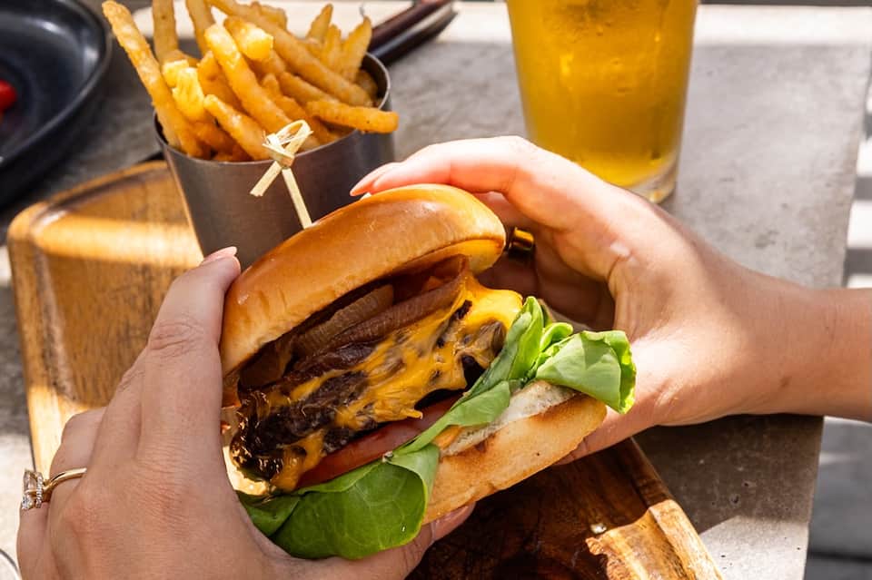 Gourmet cheeseburger with fries and beverage at outdoor dining table