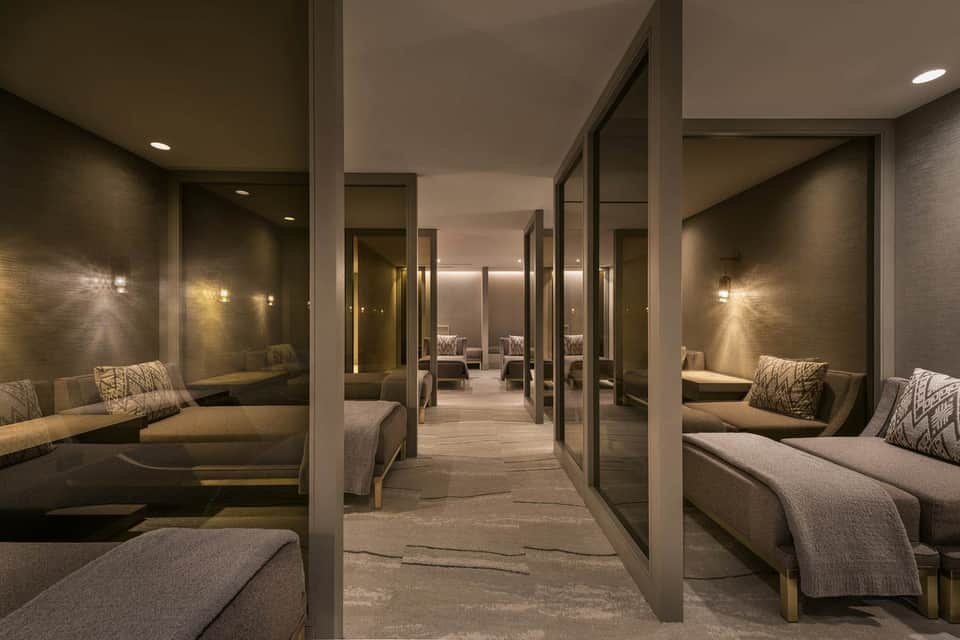 Modern spa relaxation room with mirrored walls, lounge seating, and ambient lighting throughout
