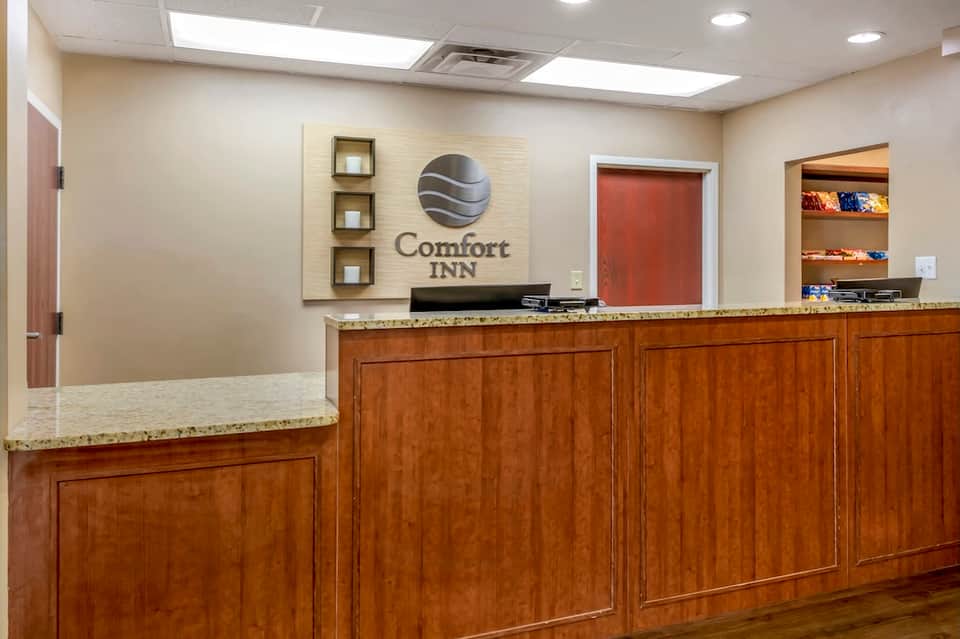 Comfort Inn front desk with wooden cabinetry, logo signage, and warm interior lighting