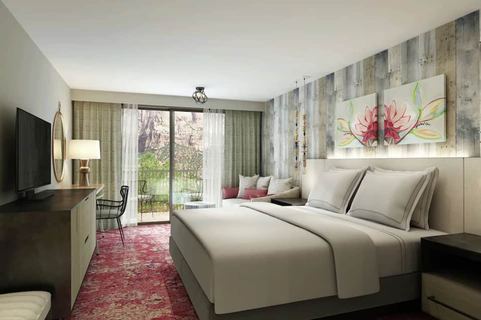 Bright hotel bedroom with king bed, garden view doors, and decorative flower artwork