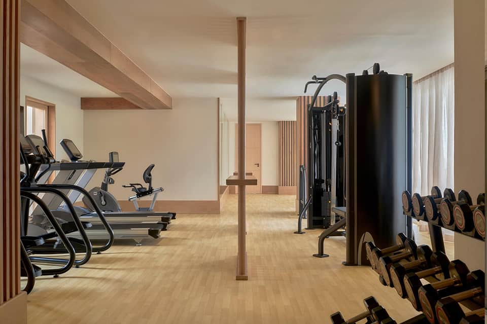 Fitness center with cardio equipment, weight racks, and natural wooden beam supports