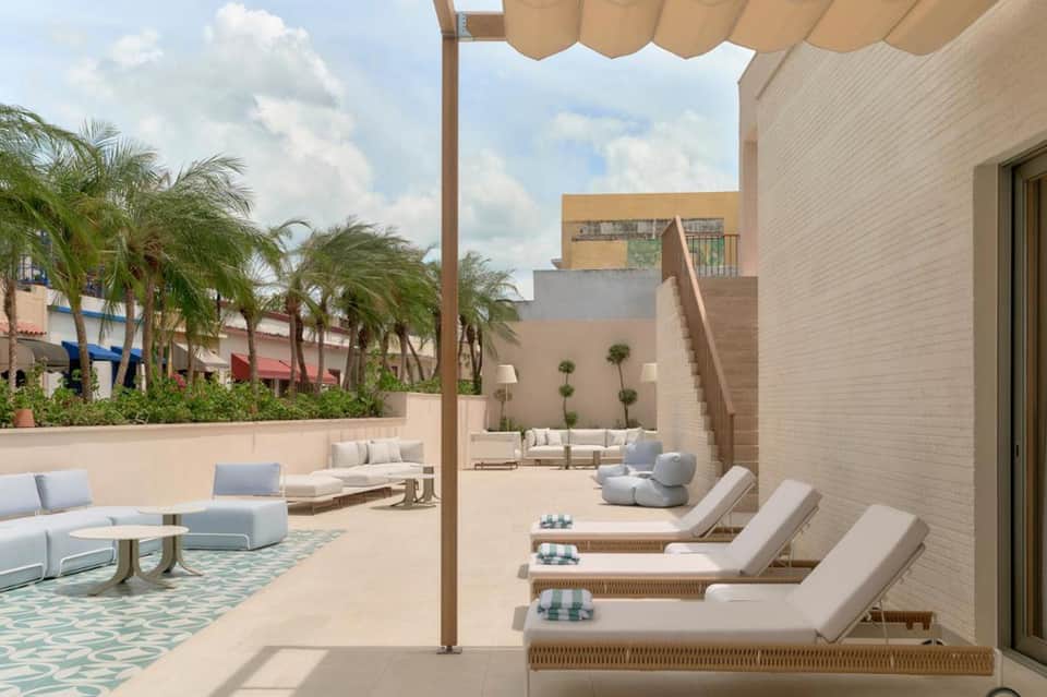Luxury terrace with neutral lounge chairs and pergola overlooking palm trees and buildings