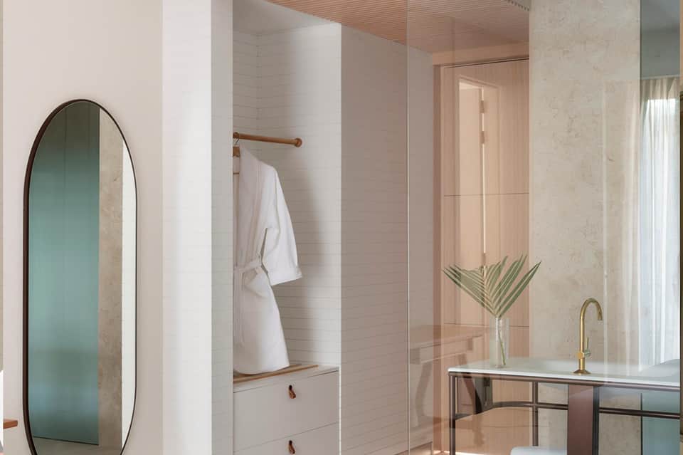 Modern bathroom featuring white subway tile, arched mirror, glass shower enclosure, and natural light