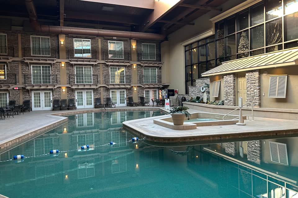 Indoor heated pool with lounge chairs and stone accent wall in hotel courtyard with modern architecture