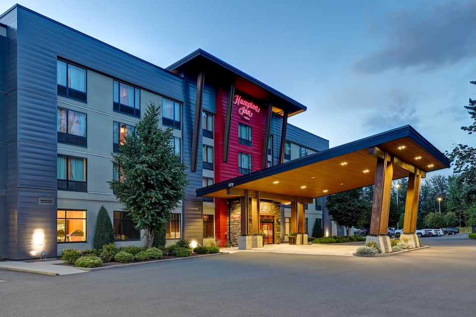 Modern Hampton Inn hotel exterior at dusk with illuminated entrance and landscaping