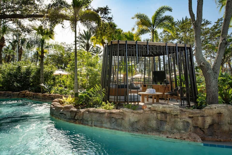 Tropical resort cabana with black frame overlooking turquoise lagoon and lush greenery
