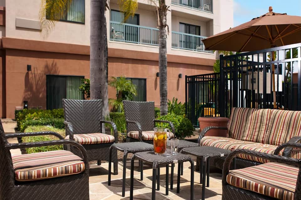 Outdoor courtyard seating area with striped cushioned furniture and large brown umbrella