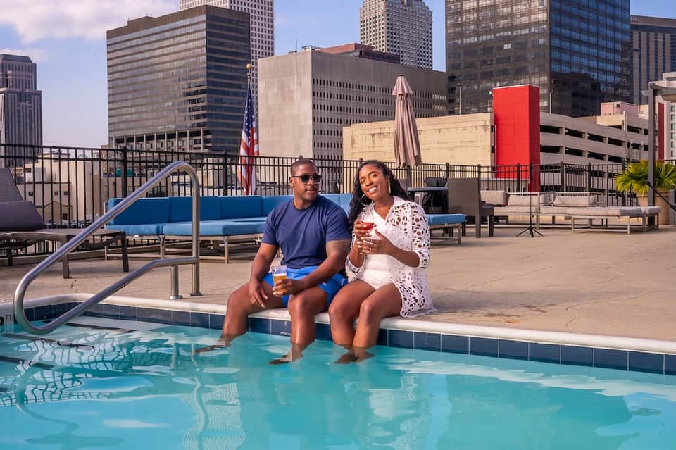 Couple relaxing by rooftop pool with downtown skyline views and summer beverages