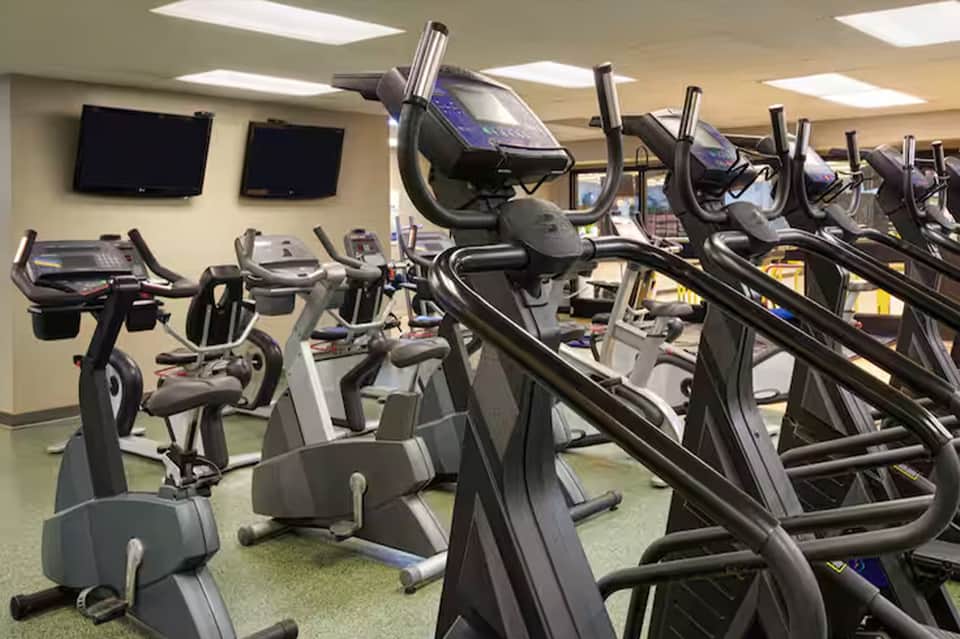Modern fitness center with stationary bikes, ellipticals, and wall-mounted monitors