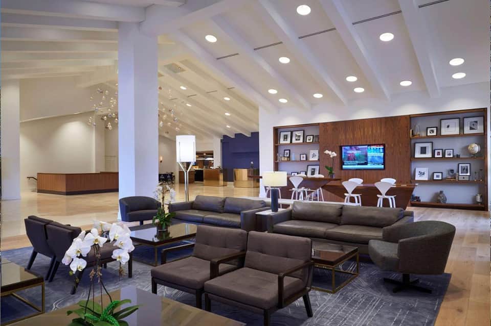 Modern hotel lobby featuring dark sofas, wood accents, marble flooring, and reception desk