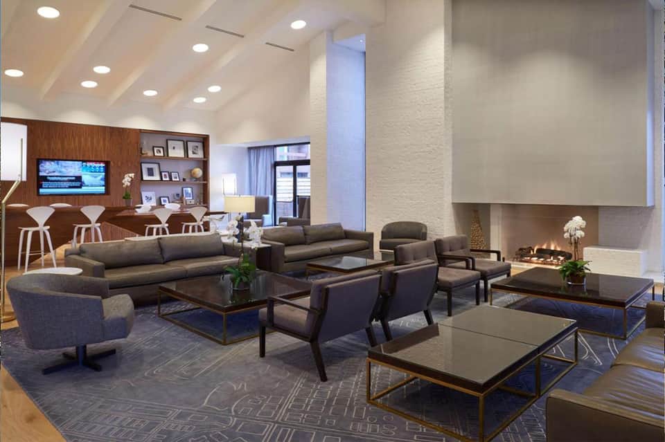 Spacious lobby lounge with high ceilings, fireplace, and modern furniture arrangement