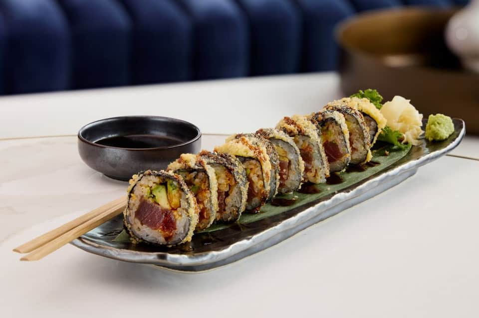 Sushi roll platter with soy sauce and garnish on white table