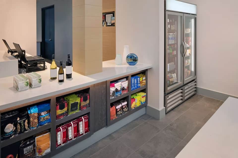 Hotel beverage station with counter, refrigerated display, snacks, and room access door