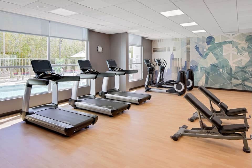 Bright fitness center with treadmills, stationary bikes, and exercise equipment near large windows