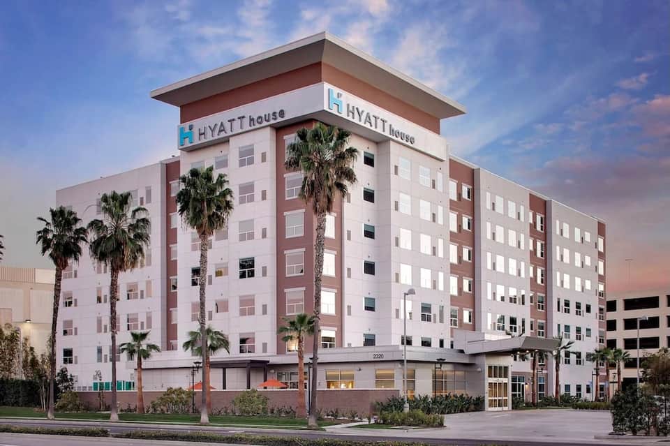 Hyatt House hotel exterior at dusk with pink and white facade