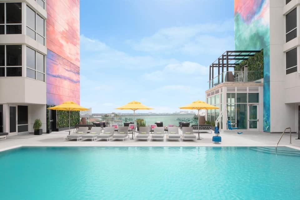 Modern pool deck with yellow umbrellas, lounge chairs, and colorful building architecture