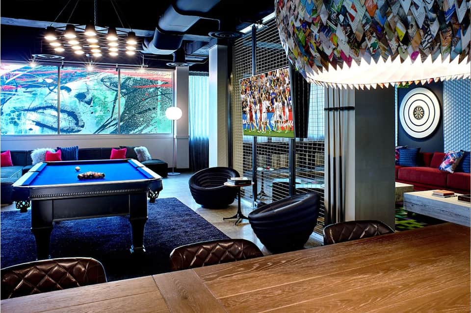 Game room with pool table, lounge seating, TV screens, and colorful accent lighting