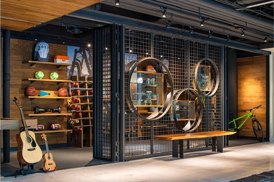 Modern sports lounge with guitars, bicycles, and circular mirrors on display shelving