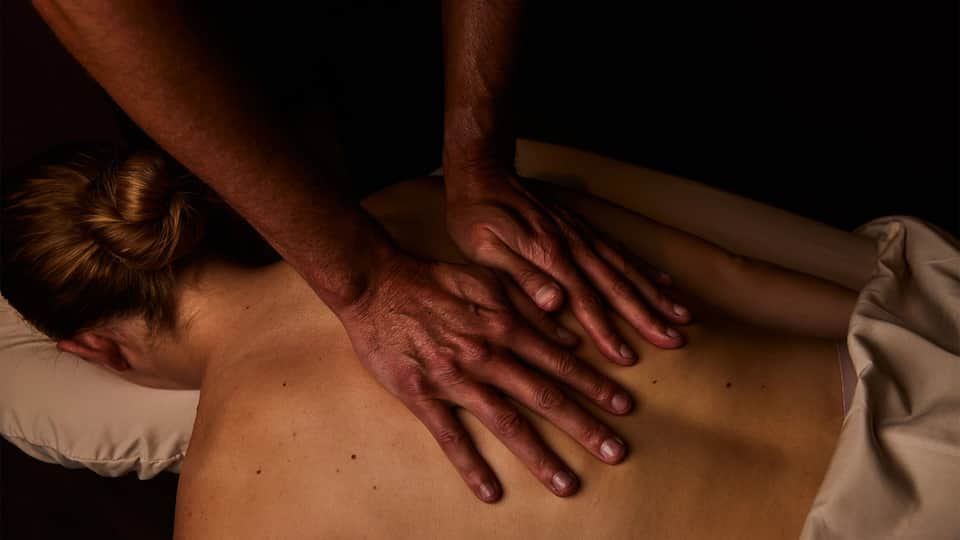 Spa massage therapy session showing therapist's hands on client's back