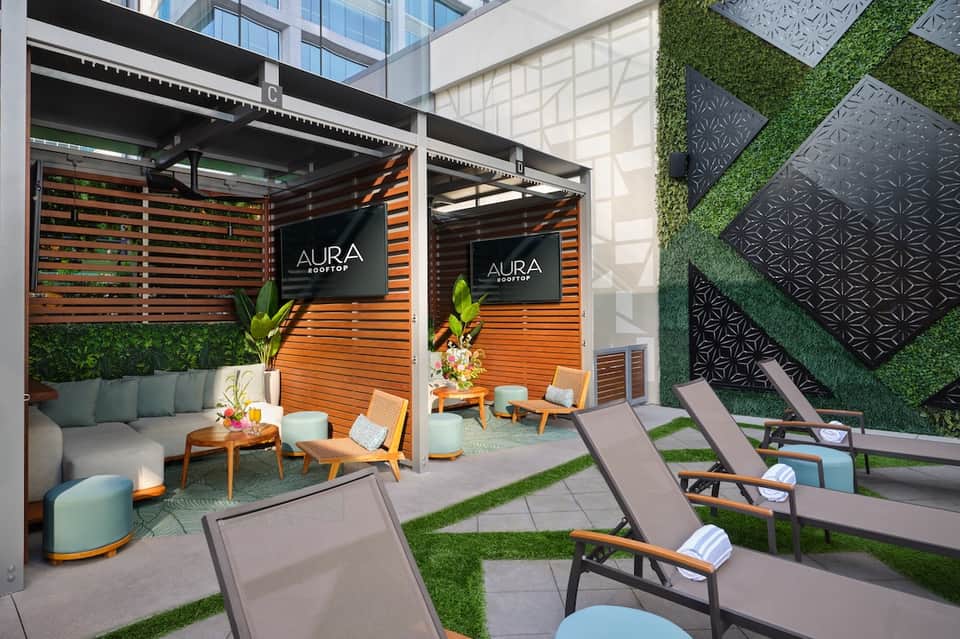 Modern rooftop lounge with orange wooden screens, lounge chairs, and artificial grass