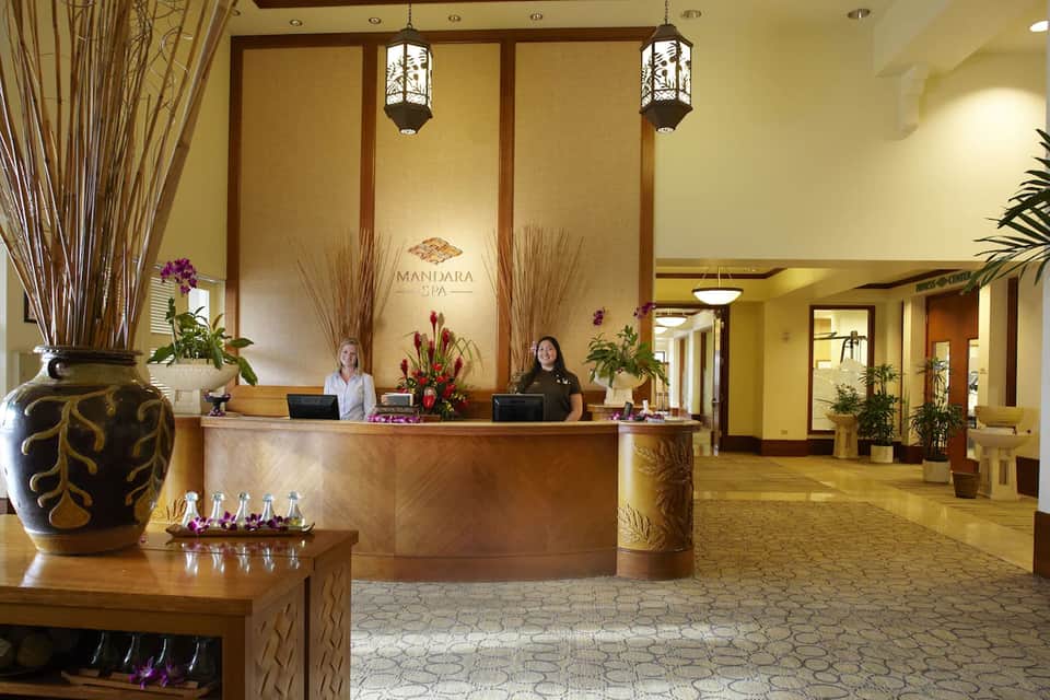 Spa reception desk with elegant wood paneling, flowers, and decorative vases in warm lighting