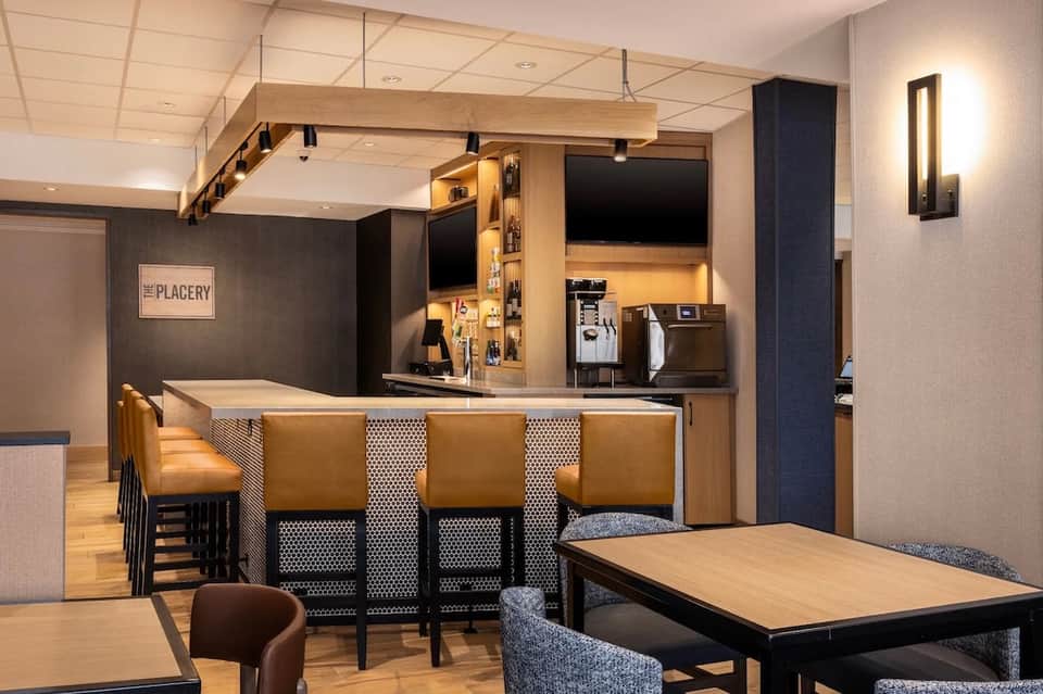 Hotel lounge and bar with wooden accents, tan leather seating, and contemporary design elements