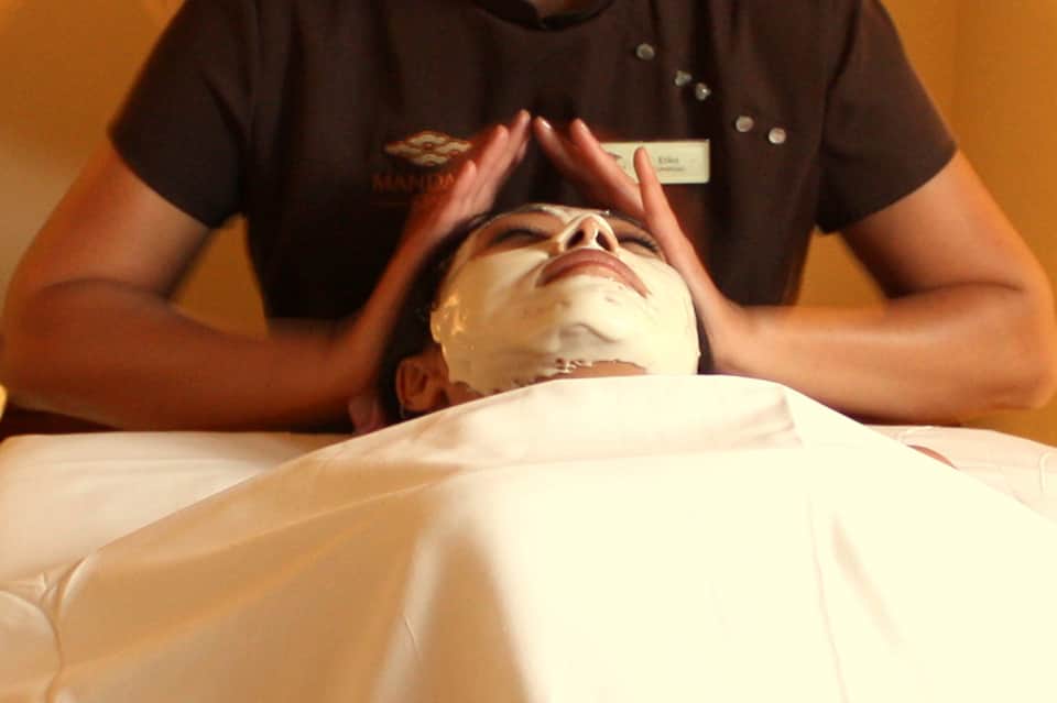 Spa therapist applying facial treatment to relaxed client on massage table